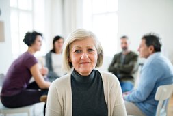 Ältere Dame sitzt vor einem Gesprächskreis mit Senioren | © Halfpoint - stock.adobe.com